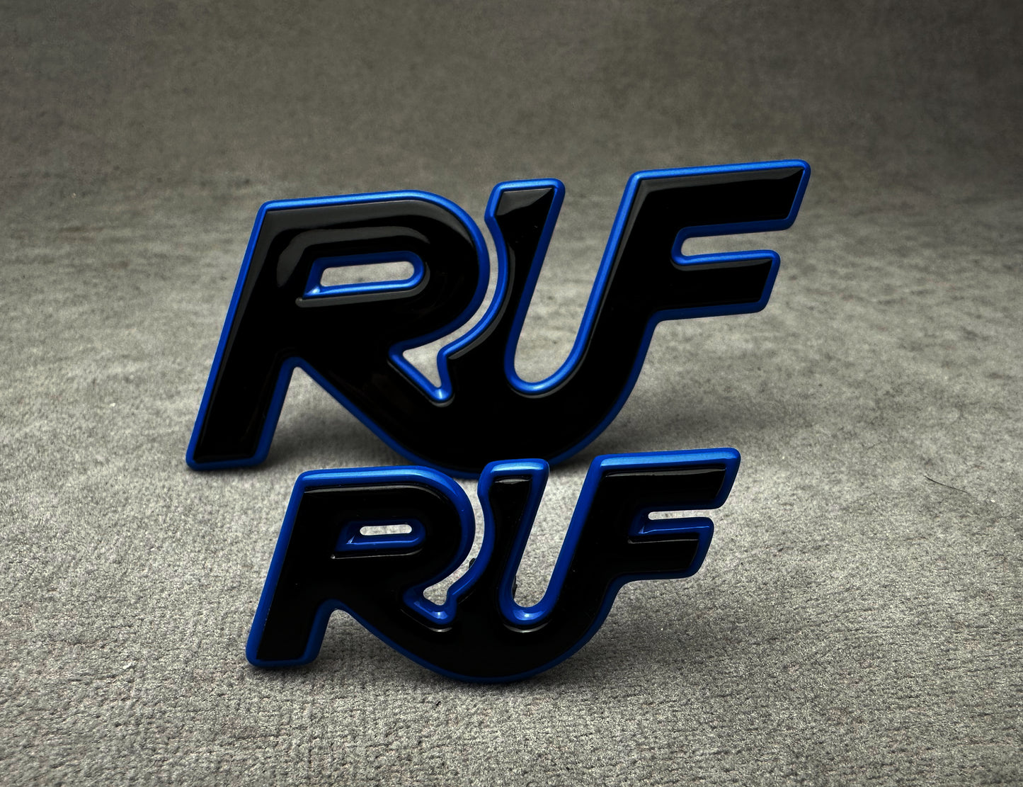 Close-up of two-piece RUF emblem badge set in black and blue metal finish
