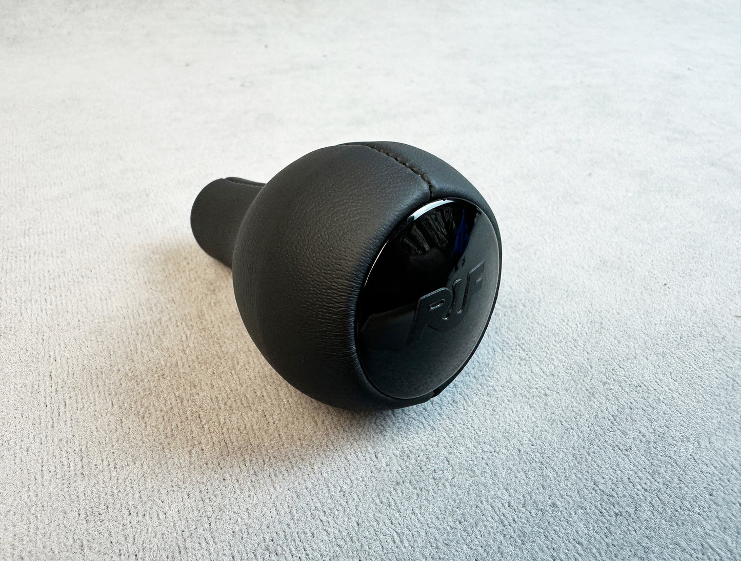 Close-up of matte black RUF logo on leather gear knob