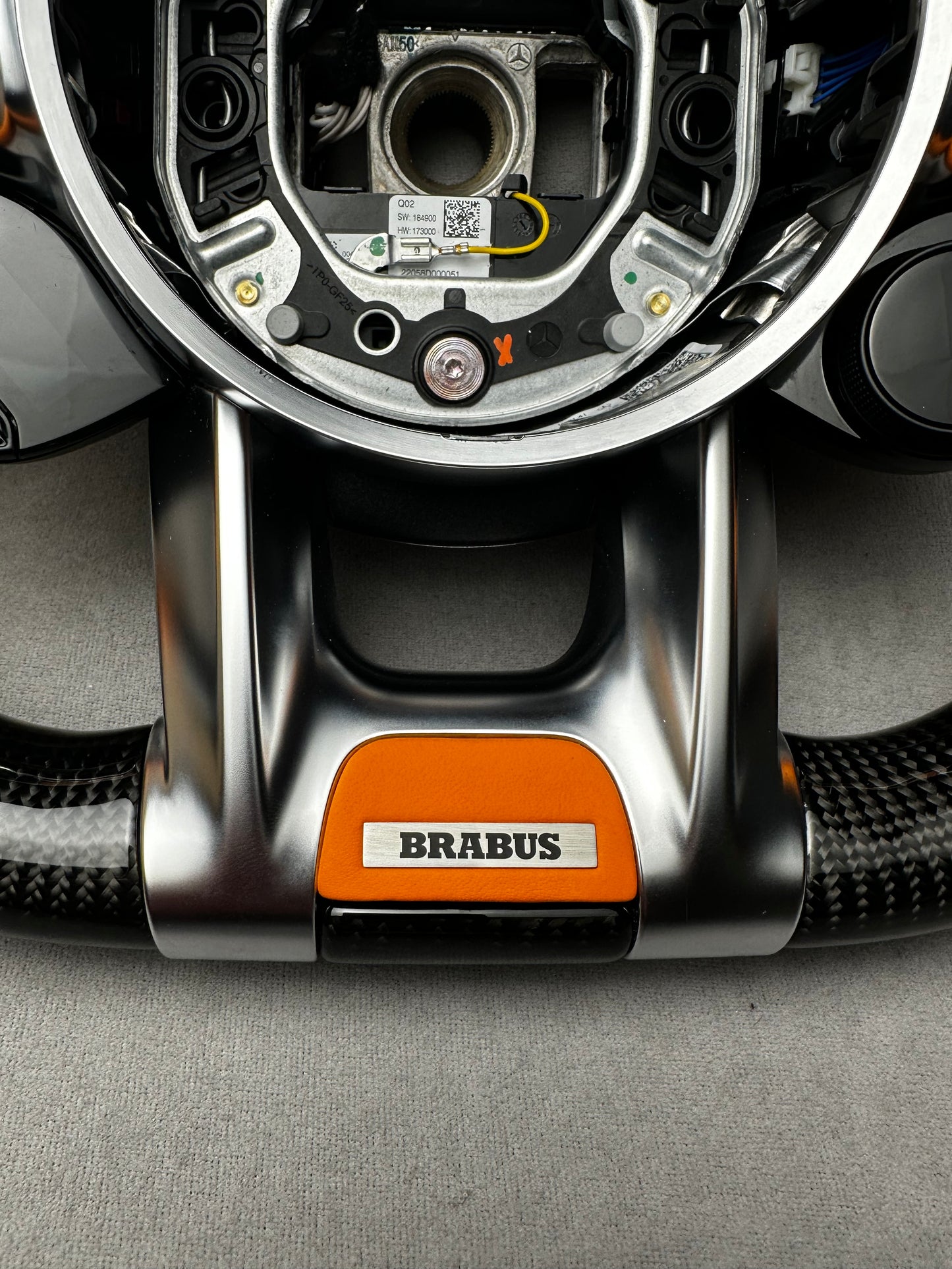 Close-up of Brabus Orange flat leather emblem on a Mercedes steering wheel