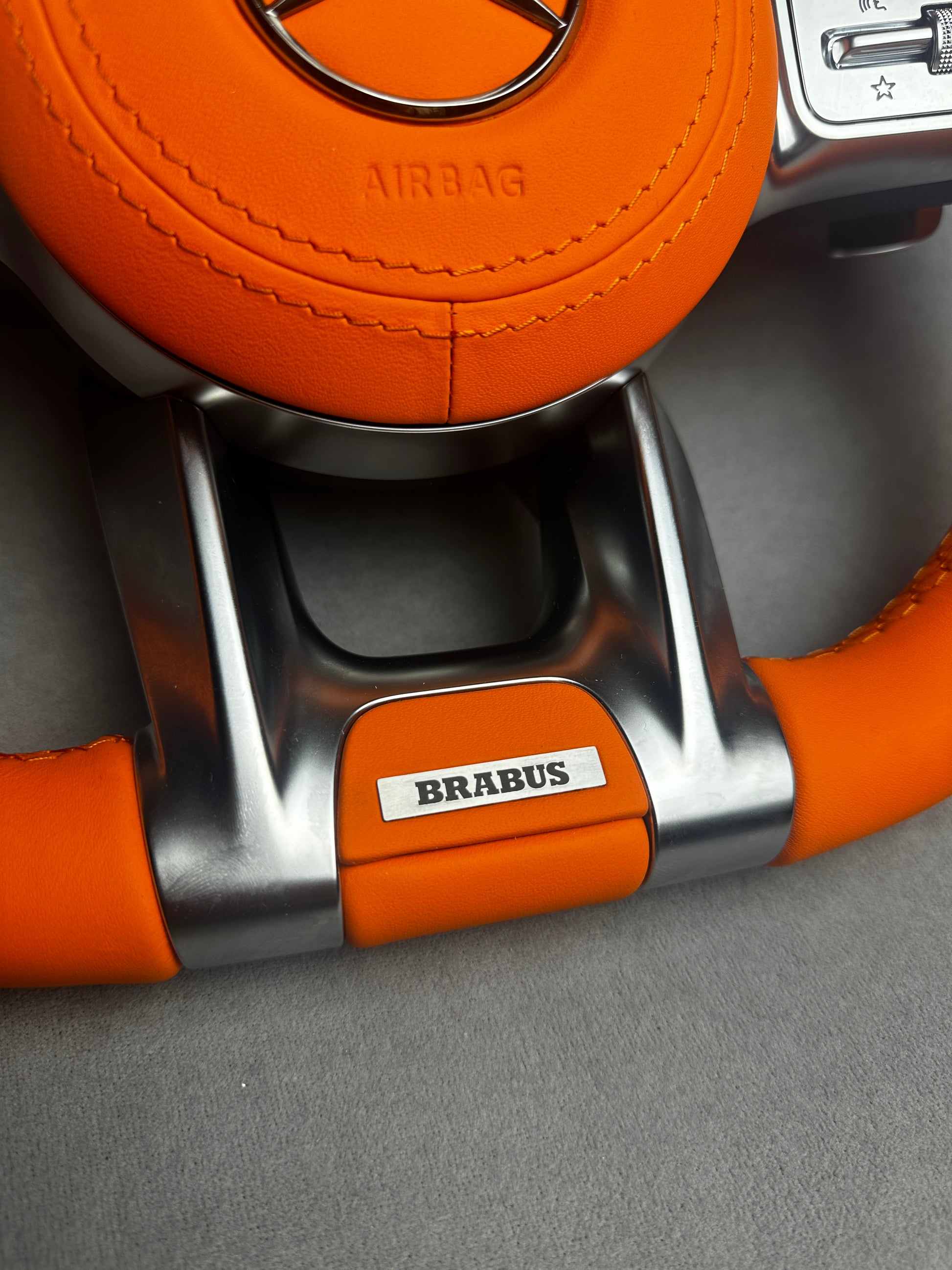 Close-up of Brabus Orange flat leather emblem on a Mercedes steering wheel
