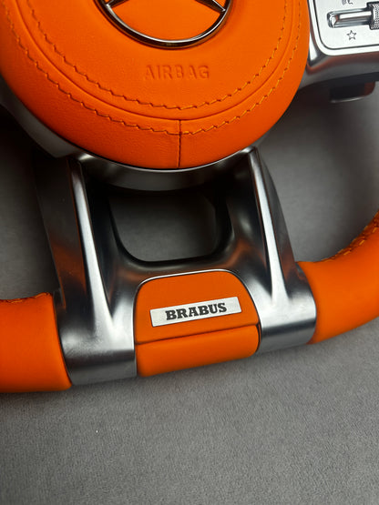 Close-up of Brabus Orange flat leather emblem on a Mercedes steering wheel