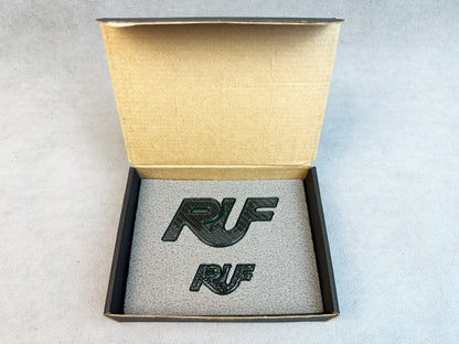 Close-up of RUF emblem with carbon fiber base and green metal finish