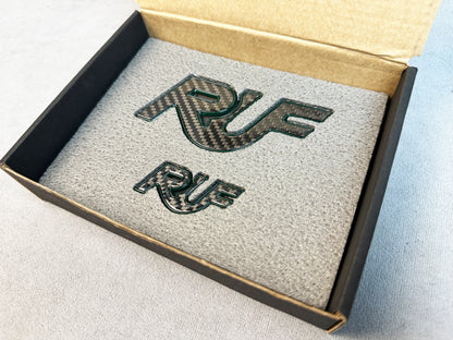 Pair of RUF Mean Green emblems on display table for Porsche 997