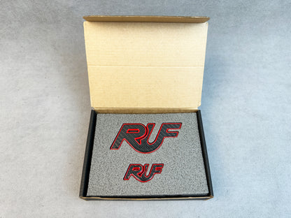 Close-up of carbon RUF emblem with bold red metal finish