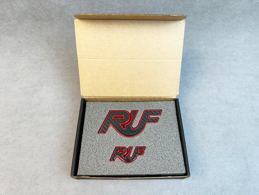 Close-up of carbon RUF emblem with bold red metal finish