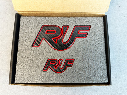 Pair of RUF carbon and red emblems displayed on premium photo zone