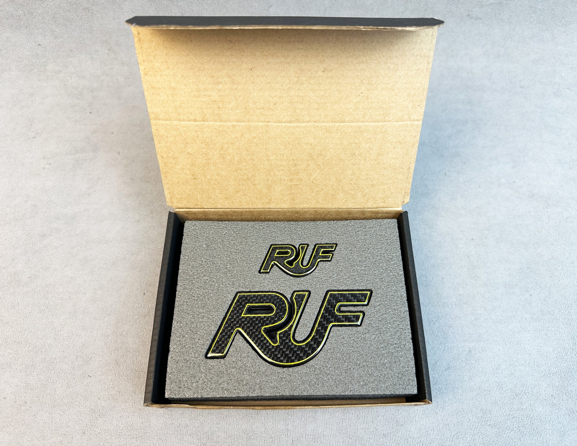 Yellow-edged carbon RUF emblem on a Porsche 997 hood