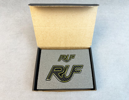 Yellow-edged carbon RUF emblem on a Porsche 997 hood