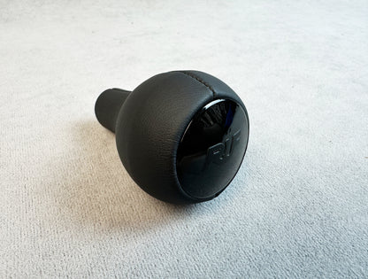Close-up of matte black RUF logo on leather gear knob