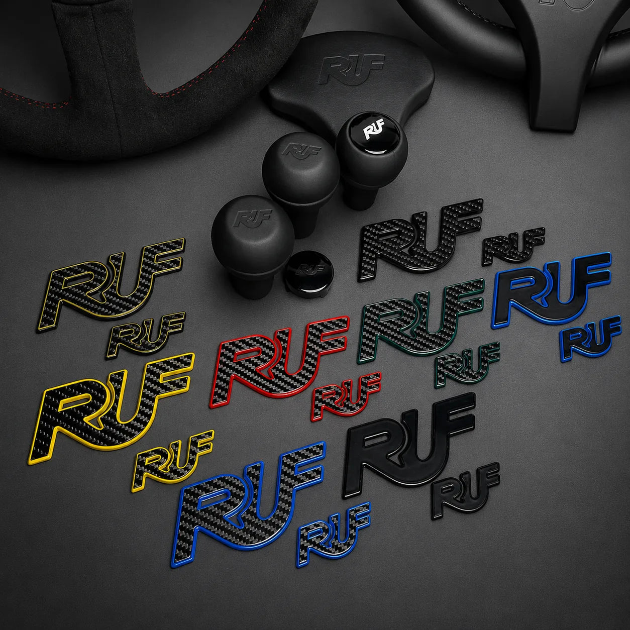 Shift knobs, steering wheels with 'RUF' branding on a dark surface, surrounded by various colored 'RUF' logos emblems.